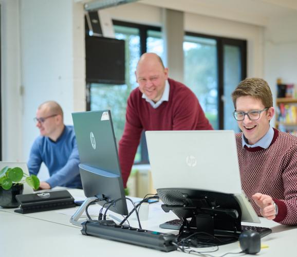 Collega\'s mact bij computerschermen op kantoor